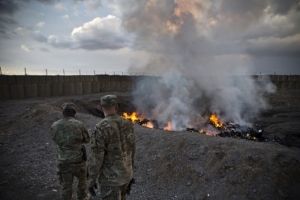 U.S. Army soldiers watch garbage burn in a burn-pit at Forward Operating Base Azzizulah in Maiwand District, Kandahar Province, Afghanistan, February 4, 2013. REUTERS/Andrew Burton (AFGHANISTAN - Tags: MILITARY) - RTR3DCLD